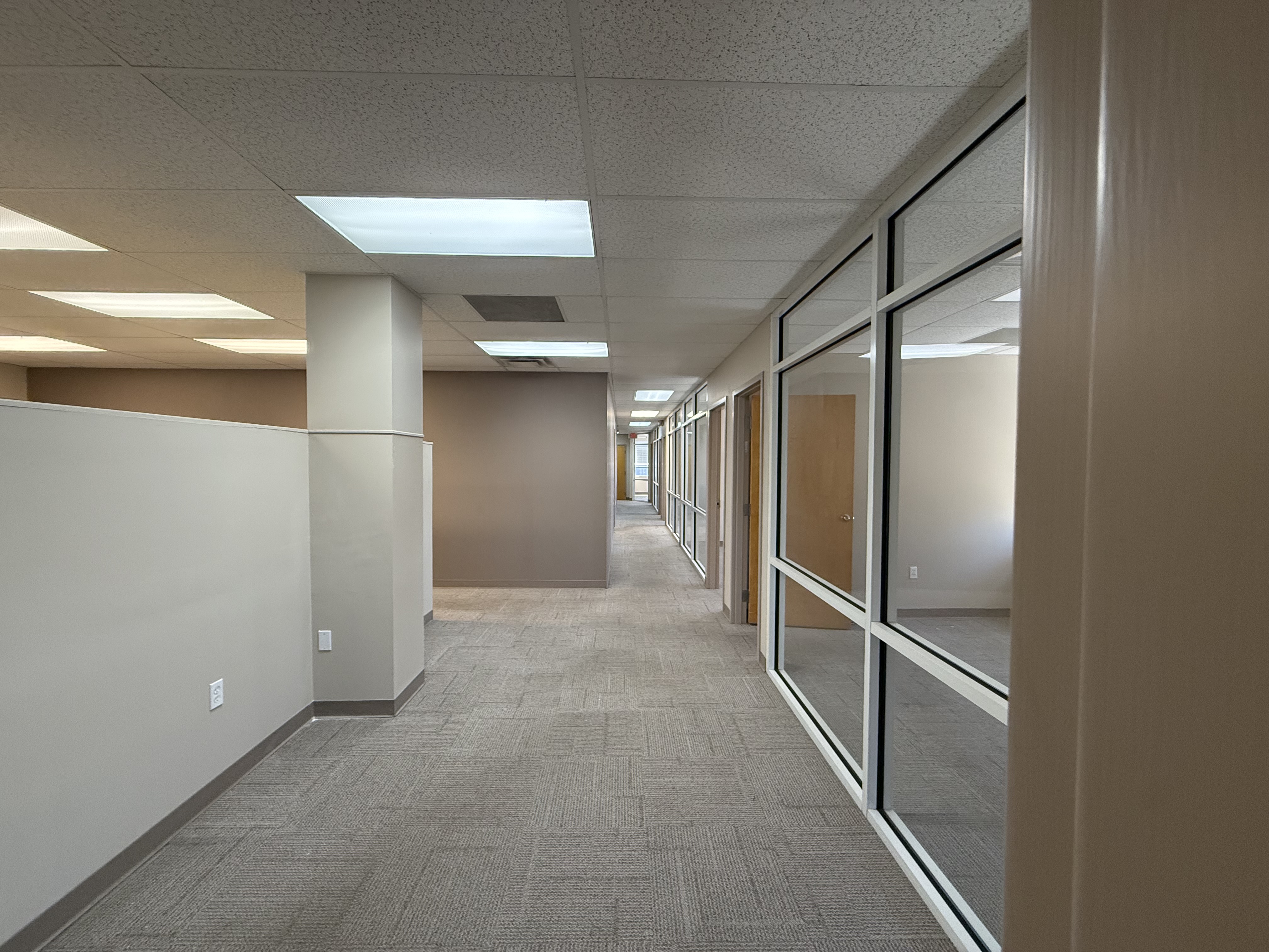 A corridor lined with glass-fronted private offices in Suite 1200